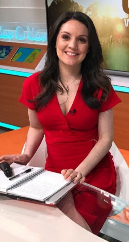 Laura Tobin smiling while seated at a news desk in a red dress.