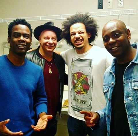 Eric Andre posing enthusiastically with comedians Chris Rock, Jeff Ross, and Dave Chappelle backstage.