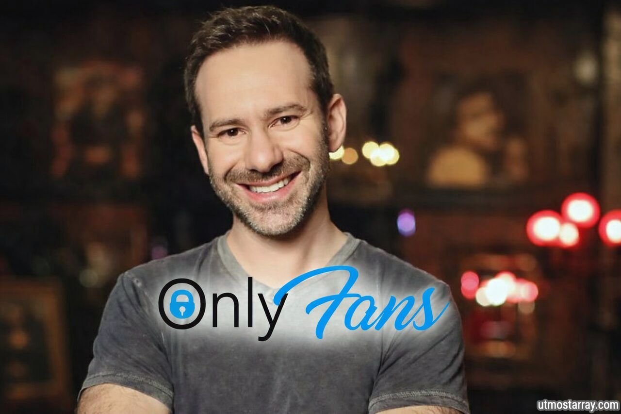 Leonid Radvinsky with OnlyFans logo overlay on chest in a dimly lit indoor setting