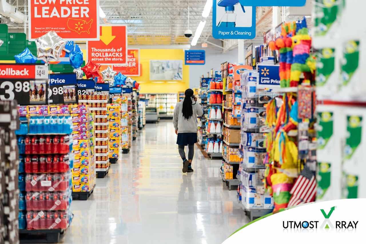 Shopper walking through a Walmart aisle with low-price signs and household products.